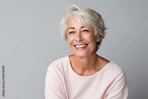 Portrait of a happy senior woman looking at camera over grey background