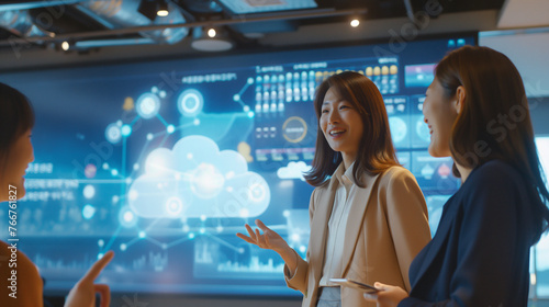 A diverse two businesswomen standing in a server room, looking at a large virtual screen with a cloud computing graphic overlay