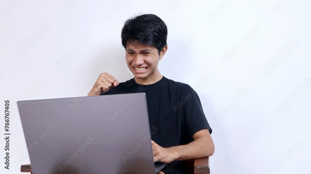 Young emotional Asian man in front of laptop Young emotional Asian man in front of laptop