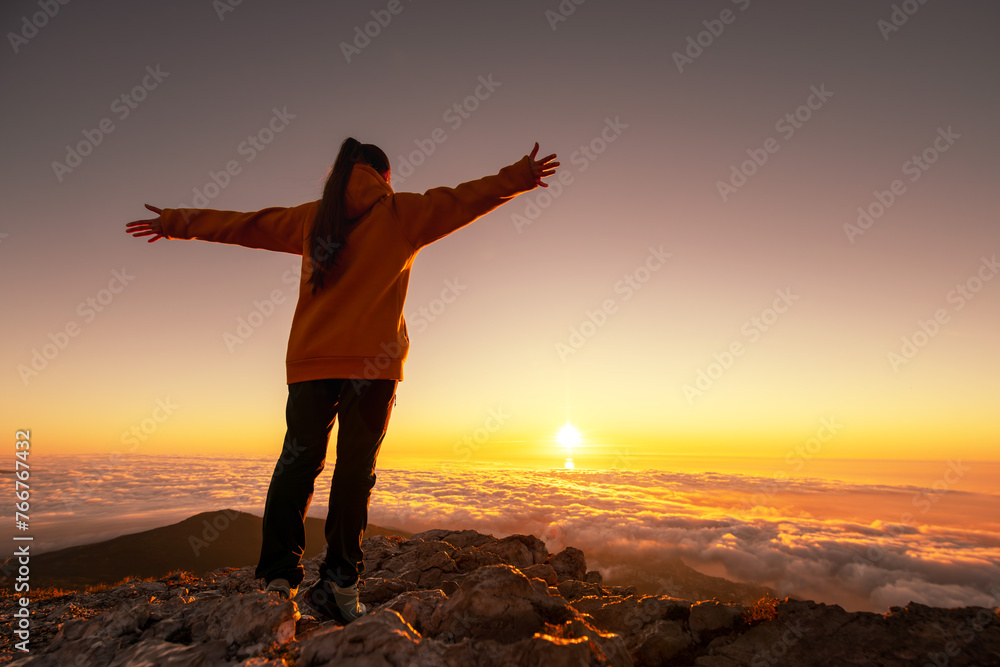 Happy hiker or tourist without backpack is standing with open arms mountain top and enjoys sunrise