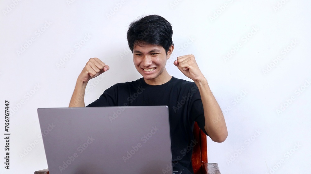Young emotional Asian man in front of laptop Young emotional Asian man in front of laptop