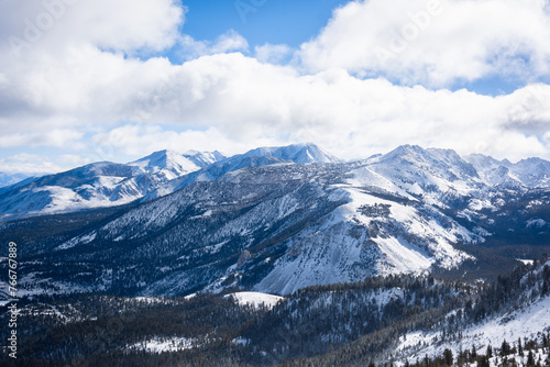 A view of snowy mountains and puffy clouds on a sunny winter day in Mammoth Lakes, CA