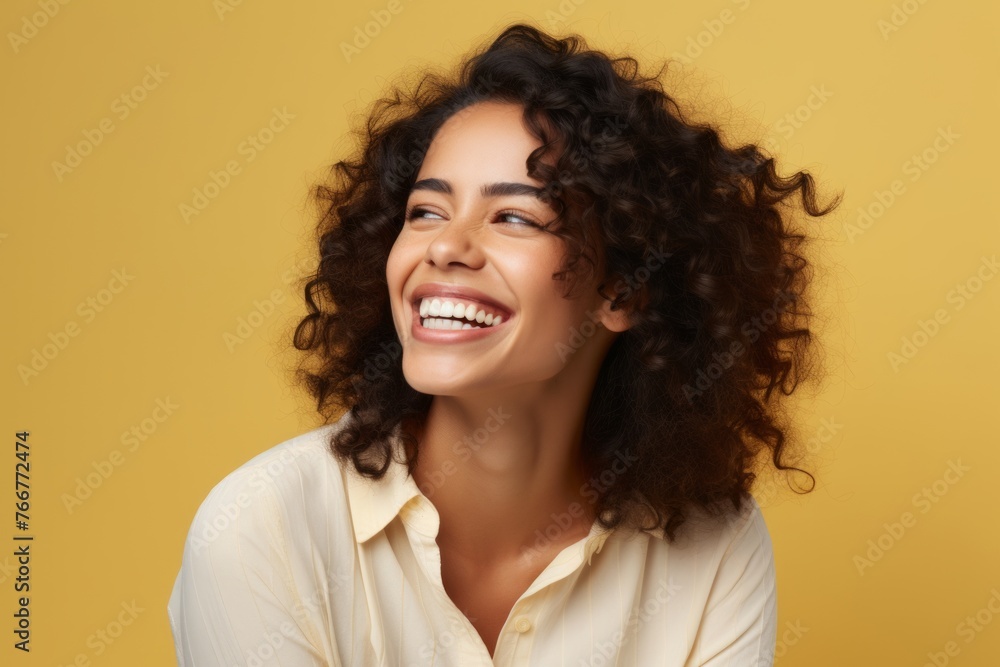 Portrait of a beautiful young woman with curly hair laughing, isolated on yellow background Portrait of a beautiful young woman with curly hair laughing, isolated on yellow background