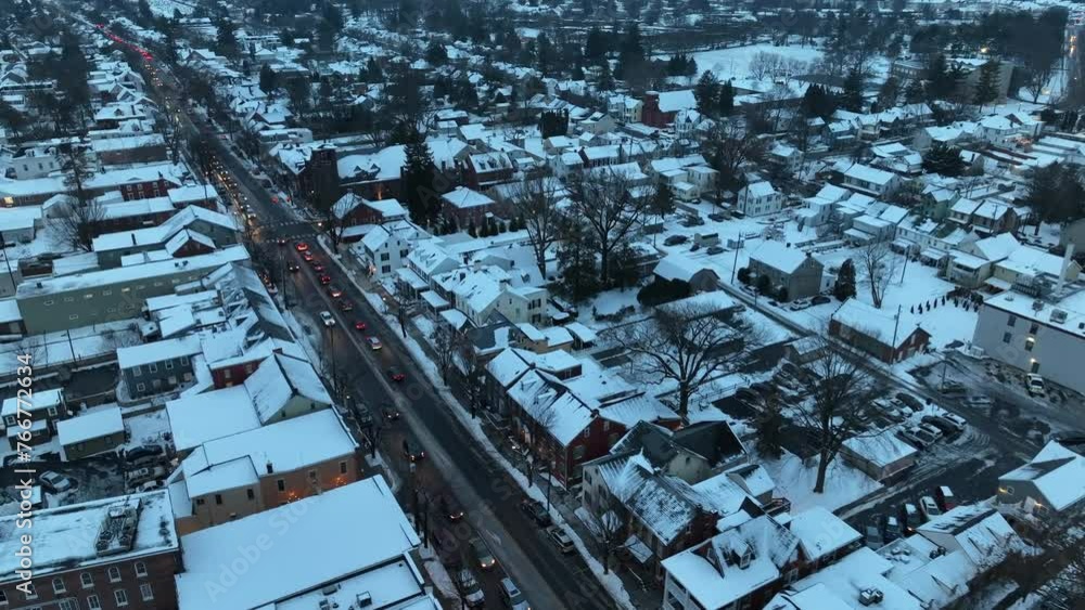 Traffic on Main Street of American Town in Snowy Town at Dusk. Snow covered neighborhood in USA. Christmas winter scene. Aerial birds eye shot. Traffic on Main Street of American Town in Snowy Town at Dusk. Snow covered neighborhood in USA. Christmas winter scene. Aerial birds eye shot.