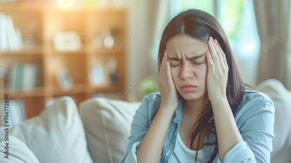 A troubled woman sits on a luxurious couch, cradling her head in her hands with a look of deep anguish on her face, Depressed frustrated young woman A troubled woman sits on a luxurious couch, cradling her head in her hands with a look of deep anguish on her face, Depressed frustrated young woman
