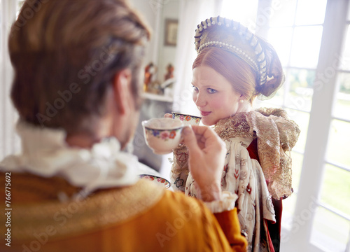 Man, woman and royal costume for tea party with conversation, vintage clothes and style in castle. King, queen and couple with drink together in morning with Victorian fashion at regal palace in UK photo