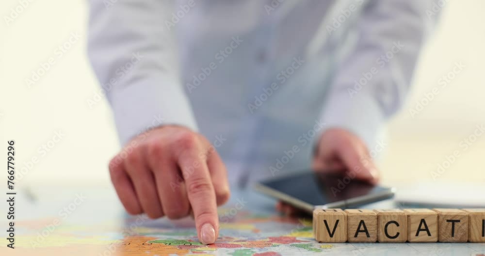 Woman index finger and cubes with word Vacation on world map Woman index finger and cubes with word Vacation on world map