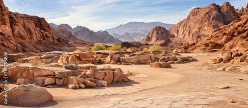 A natural landscape with mountainous landforms in the background, rocks in the foreground, under a clear sky with fluffy clouds. Perfect for travel and exploration