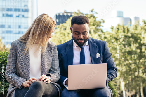 Business colleagues working with laptop outdoors