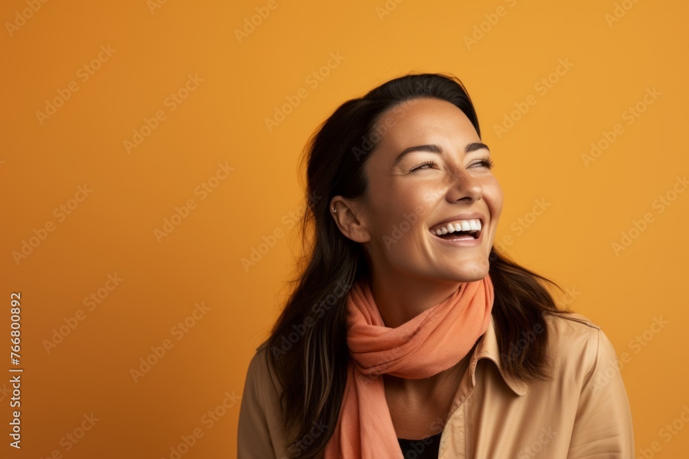 Portrait of happy young woman laughing and looking up on orange background Portrait of happy young woman laughing and looking up on orange background
