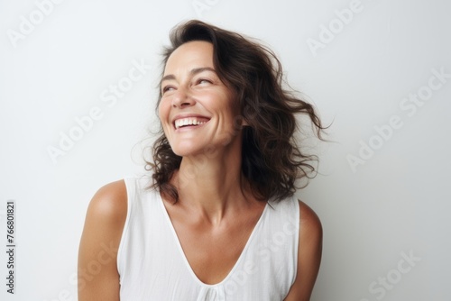 Portrait of happy young woman laughing and looking up over gray background