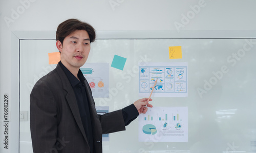 Portrait business man one oerson  Asian stand presentation holding pen and looking creative write note plan maketing idea project ready happy working online sale inside home office with intention photo