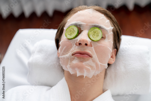 Serene daylight ambiance of spa salon, woman customer indulges in rejuvenating with luxurious cucumber facial mask. Facial skincare treatment and beauty care concept. Quiescent
