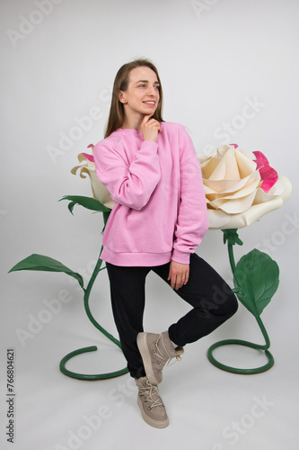 A girl athlete smiles thoughtfully against the backdrop of large artificial roses. studio shot