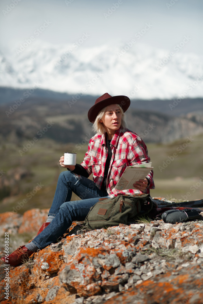 Portrait girl traveler with hat and mug on background of mountains