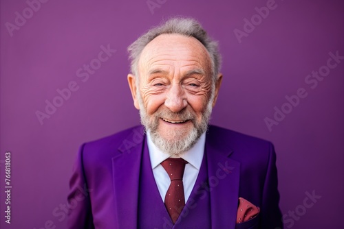 Happy senior man with grey beard and mustache in purple suit and tie.