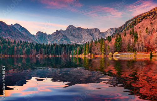 Mangart mountain range reflected in the calm waters of Fusine lake. Amazing summer sunrise in Julian Alps with huge rock on background, Province of Udine, Italy. Beauty of nature concept background.