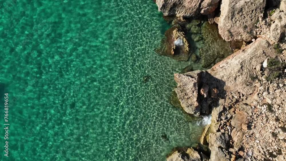 Sparkling crystal clear sea with rocky beach top down drone shot Sparkling crystal clear sea with rocky beach top down drone shot