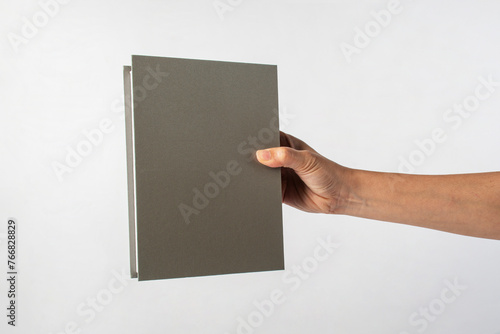Fototapeta Naklejka Na Ścianę i Meble -  Blank grey book cover in hand on white background.