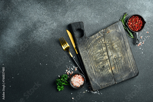 Black stone kitchen background with spices, herbs and kitchen utensils. Free space for text. Top view. Rustic style.