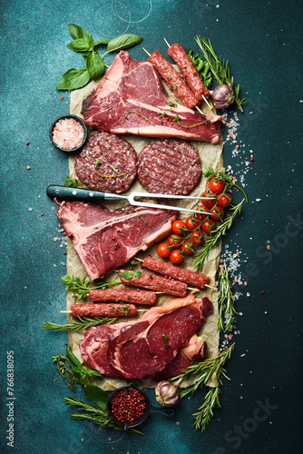 Barbecue party. T-bone steak, ribeye steak, kebab and burger patty. On a black stone background. Top view.