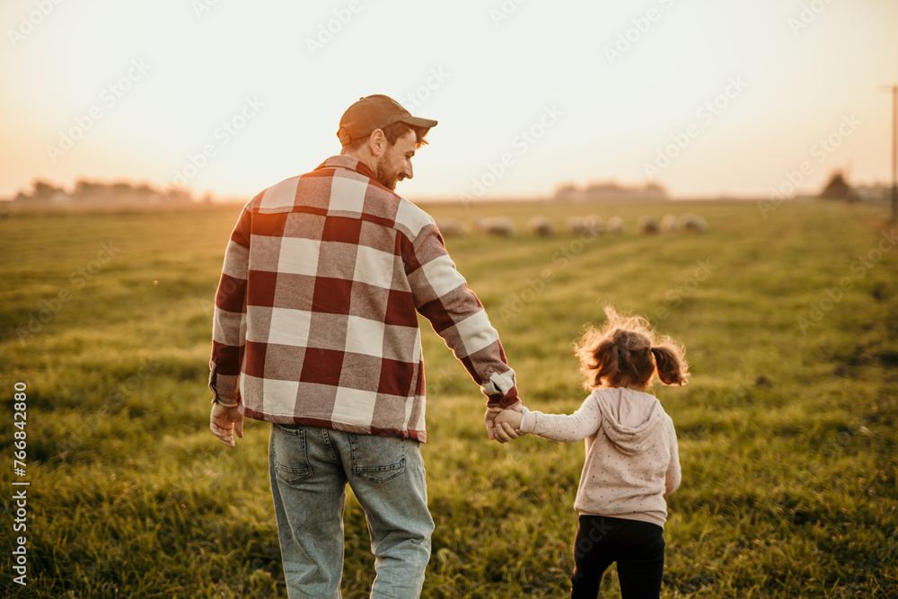 Father and daughter watching the sunset in their rustic farm field Father and daughter watching the sunset in their rustic farm field