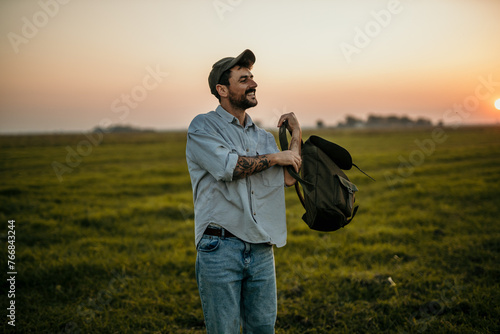 Fashionable backpacker enjoying a peaceful walk amidst rural landscapes