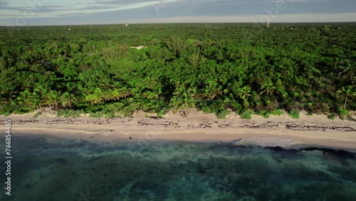 Drone aerial pan of tropical beach with ocean waves crashing on shoreline holiday destination travel tourism rainforest jungle coastline Caribbean Xpu Há Mexico photo