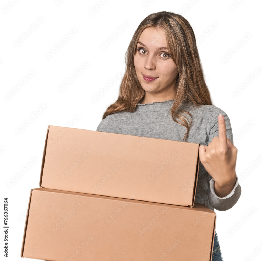 Blonde woman with cardboard boxes moving on studio backdrop pointing with finger at you as if inviting come closer. Blonde woman with cardboard boxes moving on studio backdrop pointing with finger at you as if inviting come closer.