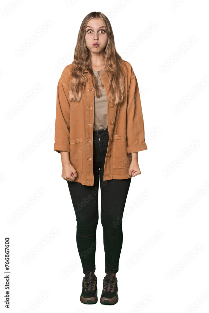 Studio portrait of a blonde Caucasian woman blows cheeks, has tired expression. Facial expression concept. Studio portrait of a blonde Caucasian woman blows cheeks, has tired expression. Facial expression concept.