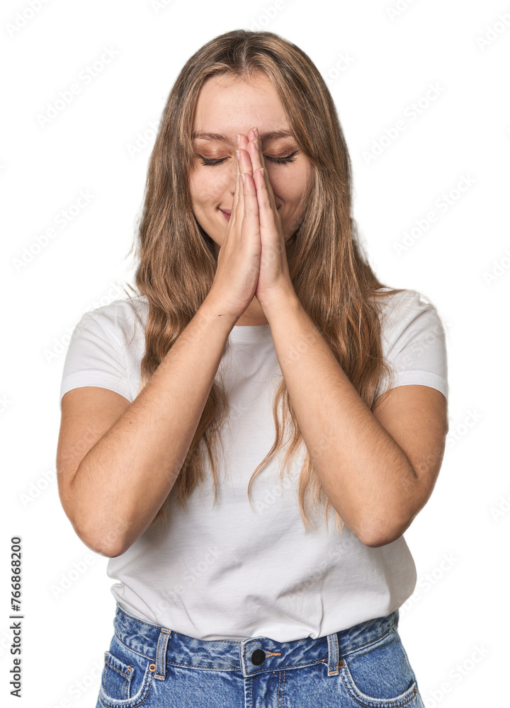 Studio portrait of a blonde Caucasian woman holding hands in pray near mouth, feels confident. Studio portrait of a blonde Caucasian woman holding hands in pray near mouth, feels confident.