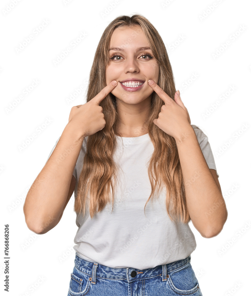 Studio portrait of a blonde Caucasian woman smiles, pointing fingers at mouth. Studio portrait of a blonde Caucasian woman smiles, pointing fingers at mouth.