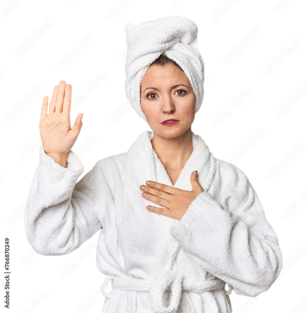 Caucasian woman in bathrobe and towel taking an oath, putting hand on chest. Caucasian woman in bathrobe and towel taking an oath, putting hand on chest.