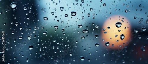 Water droplets cling to a window, creating a blurry background with hints of electric blue. The moisture reflects light in circular patterns, showcasing the beauty of precipitation