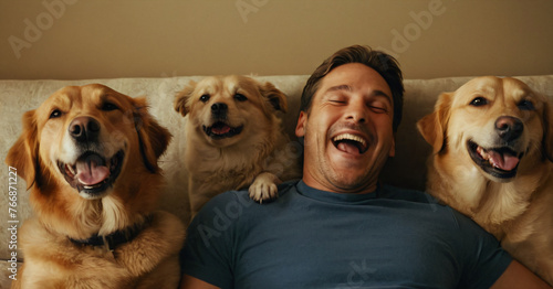A young man lies and smiles with his dogs. Funny animals