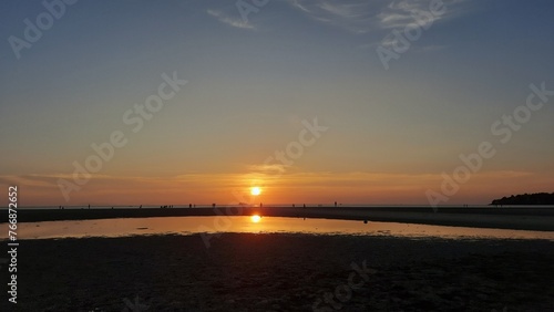 People silhouette are experiencing pure joy as they gather on the beach, delighting in the mesmerizing sunset.