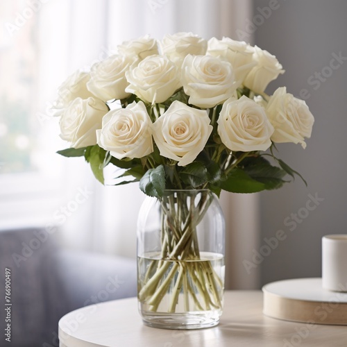 A clear glass vase filled with fresh white roses on a white shelf