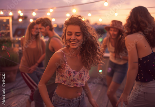 Young friends having fun dancing at a rooftop party with fairy lights
