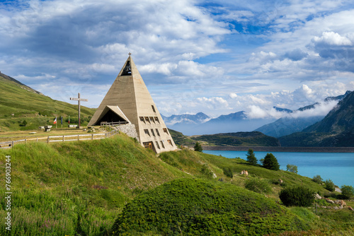 Pyramid shaped modern church and alpine lake in France.