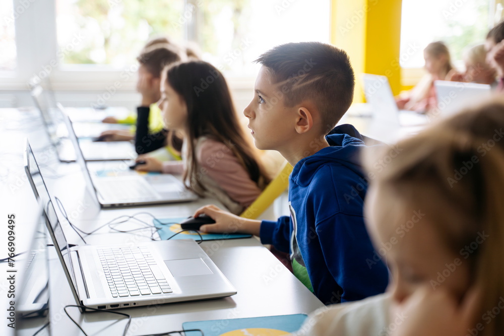 Dedicated boy using laptop learning computer coding in classroom Dedicated boy using laptop learning computer coding in classroom