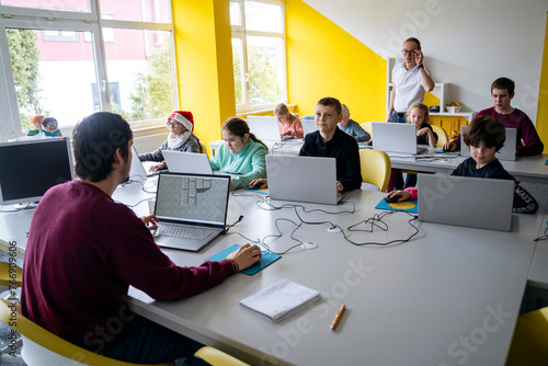 Students learning coding through laptops in classroom photo