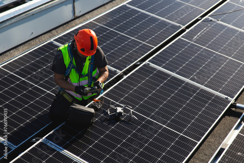 Mature technician with drone sitting on solar panel photo