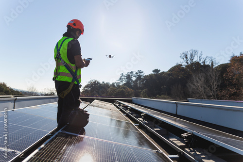 Mature engineer flying drone standing by solar panel photo