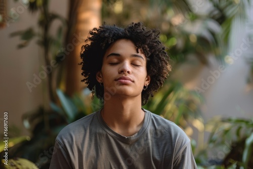 A young man sits in a meditation position, focusing inward with closed eyes