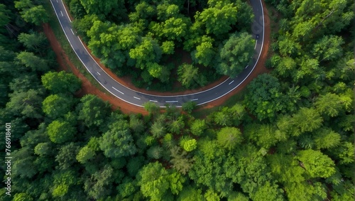 Overhead view of a road's elegant curves embracing the vibrant greenery of a forest in the monsoon period Generative AI © Haroon