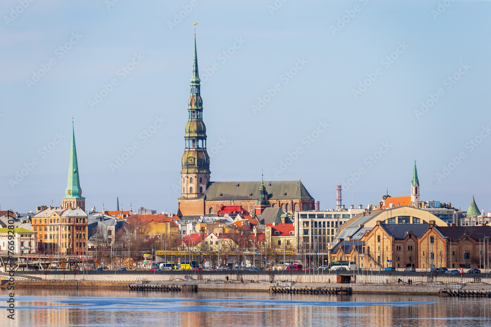 Fototapeta premium Riga towers and rooftops day time skyline. Sunny spring time shade on the buildings in Riga, next to a market and new project of railway in the Baltic States