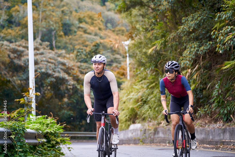 Fototapeta premium young asian adult couple cyclists riding bike on rural road