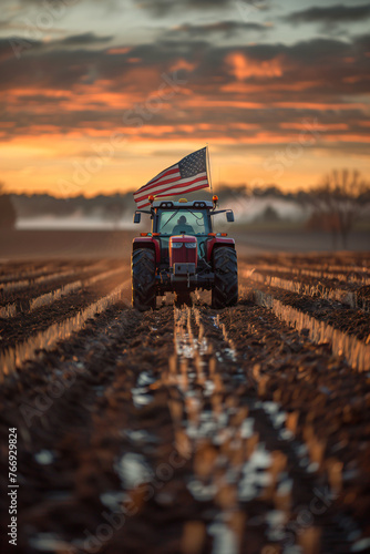 Tractor plowing fields at sunset with American flag. Agriculture and farming industry concept for design and print. Rural landscape and modern farm machinery photography