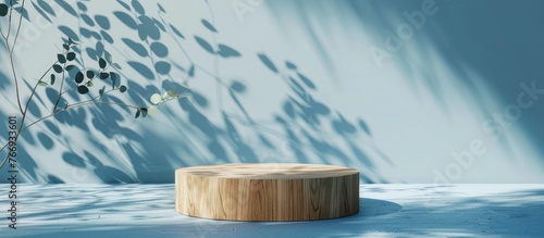 Wooden podium with eucalyptus leaves casting shadows on a blue background, designed as a stand for showcasing products. ed in 3D with a minimalistic concept, serving as an advertising template.