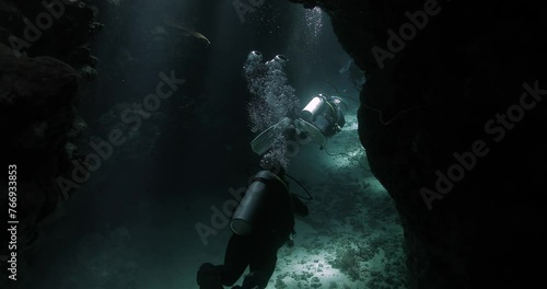 divers enter a mysterious  cave at the seabed photo